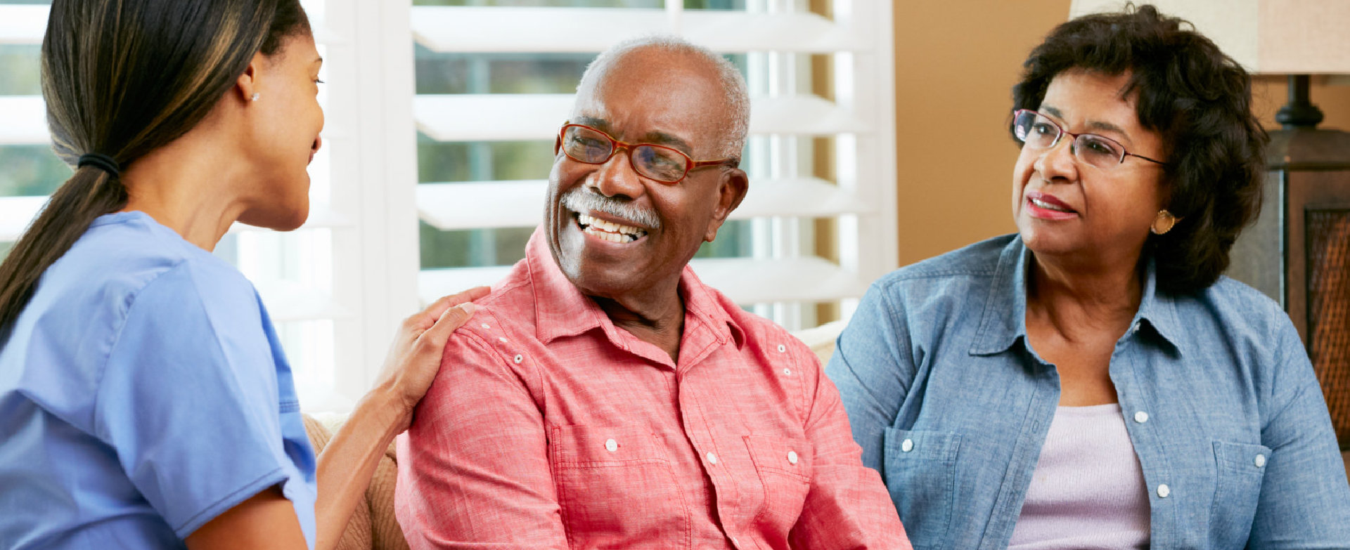 caregiver and a senior couple smiling